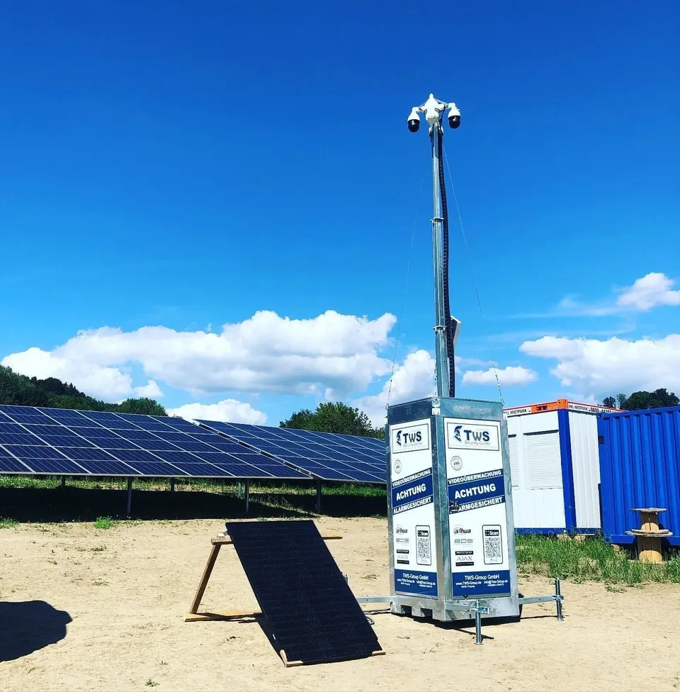 TWS Videoturm mit Beschilderung Videoüberwachung und Alarmsicherung auf einer Freifläche neben PV-Modulen